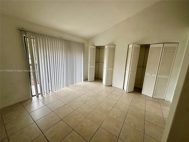 10023 SW 77th Ct, Miami, FL 33156 - unfurnished bedroom featuring light tile patterned floors, vaulted ceiling, and two closets