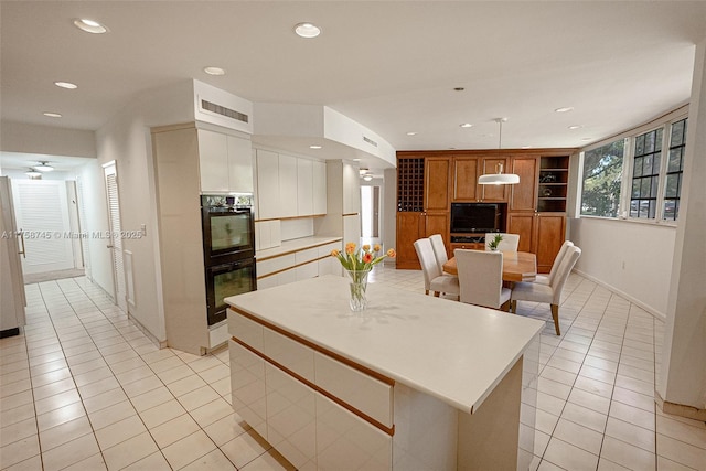 kitchen with light tile patterned floors, recessed lighting, dobule oven black, and light countertops