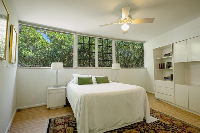 bedroom with light wood-type flooring, baseboards, multiple windows, and ceiling fan