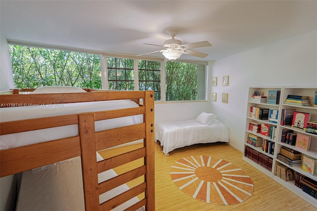 bedroom with ceiling fan, multiple windows, and wood finished floors