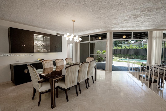 dining room featuring visible vents, a textured ceiling, an inviting chandelier, and expansive windows