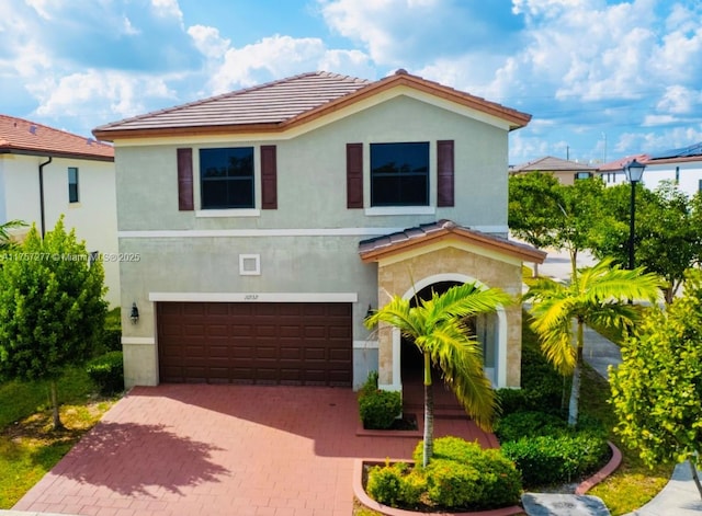 view of front of home with a tile roof, decorative driveway, an attached garage, and stucco siding