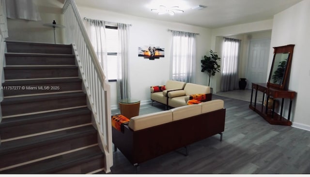 living area with stairs, wood finished floors, visible vents, and baseboards