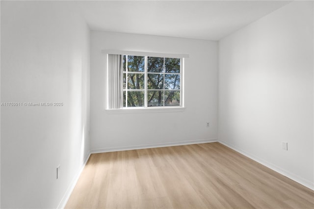 unfurnished room with baseboards and light wood-style flooring