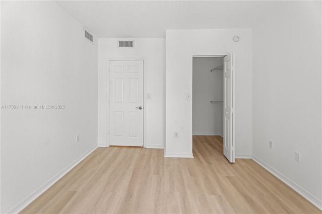 unfurnished bedroom featuring visible vents, light wood-style floors, and a spacious closet