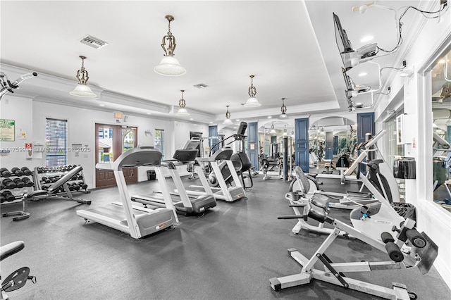 workout area featuring visible vents, a raised ceiling, and ornamental molding