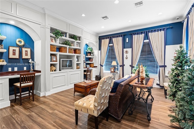 living area with visible vents, crown molding, and wood finished floors