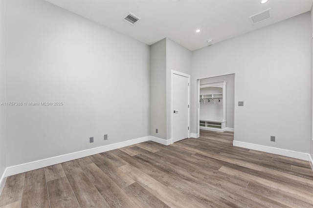 unfurnished room featuring recessed lighting, wood finished floors, visible vents, and baseboards