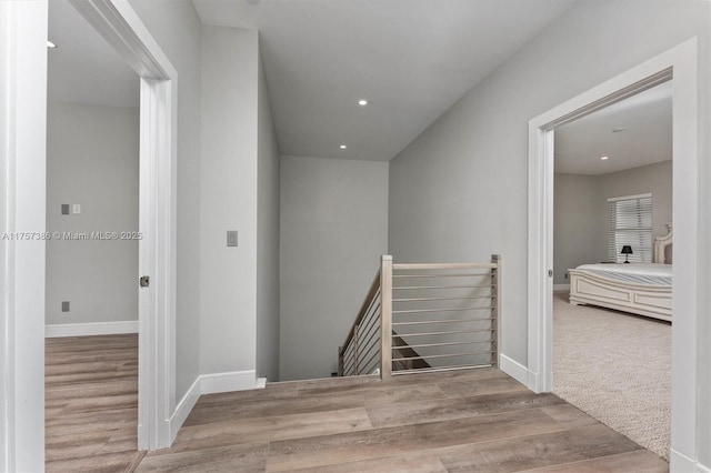 hallway with recessed lighting, baseboards, an upstairs landing, and wood finished floors