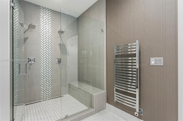 full bathroom featuring radiator, marble finish floor, and a shower stall