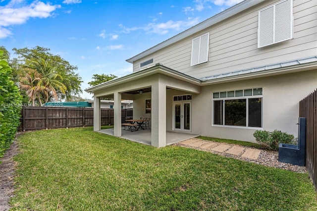 back of house with fence, stucco siding, a patio, a yard, and a standing seam roof