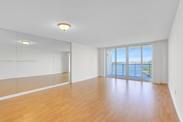 1175 NE Miami Gardens Dr Unit 610, Miami, FL 33179 - empty room featuring floor to ceiling windows, wood finished floors, a water view, and baseboards