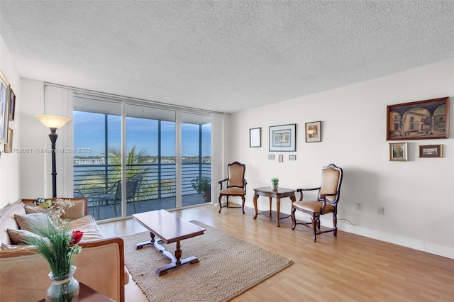 1175 NE Miami Gardens Dr Unit 610, Miami, FL 33179 - living area featuring a wall of windows, a textured ceiling, light wood-style floors, a water view, and baseboards