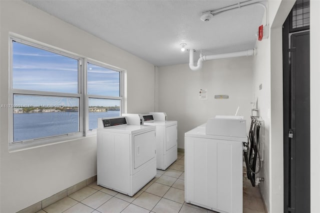 1175 NE Miami Gardens Dr Unit 610, Miami, FL 33179 - communal laundry room featuring washing machine and clothes dryer, a water view, light tile patterned floors, baseboards, and a textured ceiling