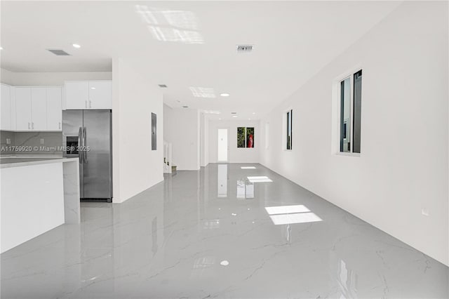 interior space with visible vents, marble finish floor, stainless steel refrigerator with ice dispenser, and white cabinetry