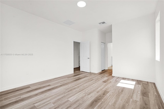 spare room featuring light wood-type flooring, visible vents, and baseboards