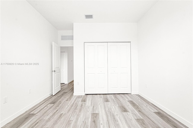 unfurnished bedroom featuring a closet, baseboards, visible vents, and light wood finished floors