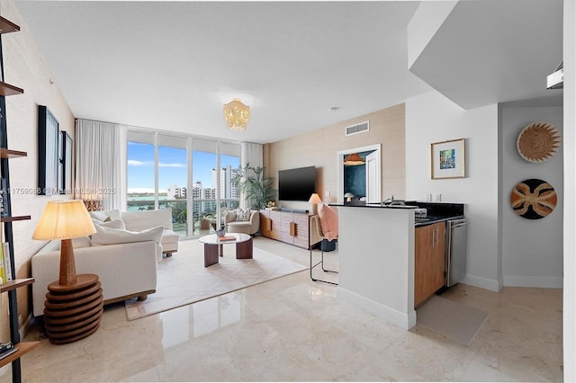 living area featuring visible vents, marble finish floor, baseboards, and expansive windows