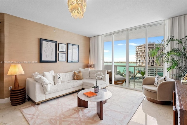 living room featuring floor to ceiling windows, a water view, and a textured ceiling