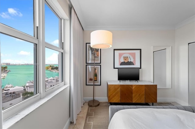 bedroom featuring crown molding, baseboards, and a water view