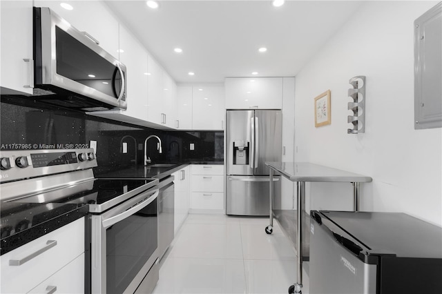 kitchen featuring tasteful backsplash, stainless steel appliances, white cabinetry, modern cabinets, and a sink