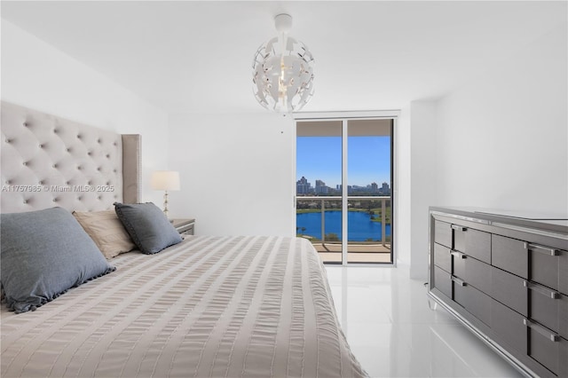 tiled bedroom featuring access to exterior, a notable chandelier, a wall of windows, and a water view