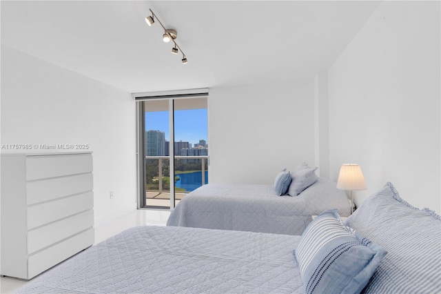 bedroom with a wall of windows, a view of city, access to exterior, and rail lighting