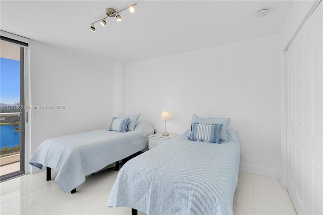 tiled bedroom with a water view, baseboards, and expansive windows