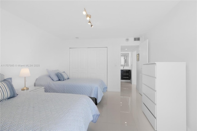 bedroom with light tile patterned floors, visible vents, and a closet