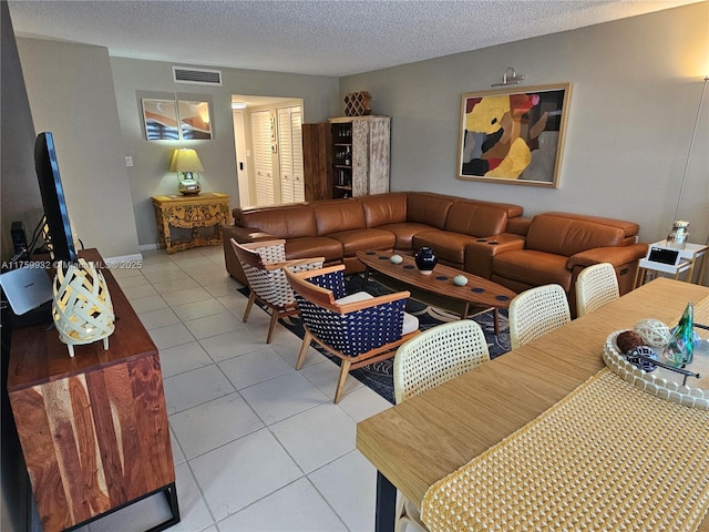 living area featuring light tile patterned floors, visible vents, a textured ceiling, and baseboards