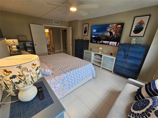 bedroom featuring a textured ceiling, light tile patterned floors, visible vents, and ceiling fan