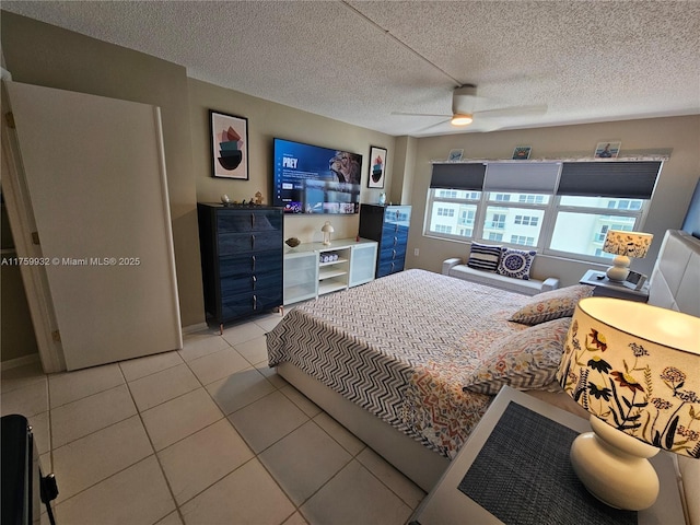 bedroom with ceiling fan, light tile patterned flooring, and a textured ceiling