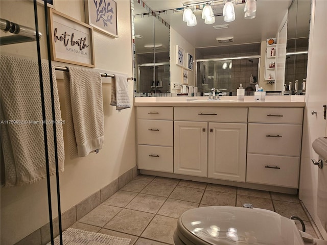 full bathroom featuring vanity, baseboards, a stall shower, tile patterned floors, and toilet