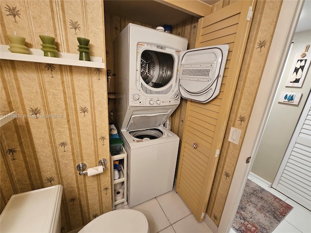 washroom with light tile patterned floors, stacked washer / drying machine, and laundry area