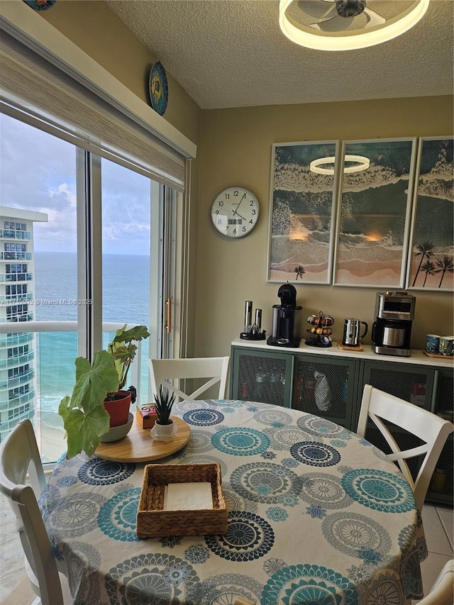 dining room featuring a water view and a textured ceiling