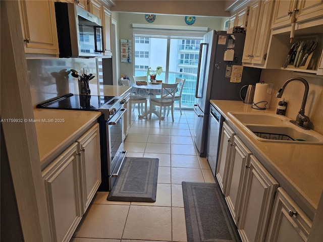 kitchen with light tile patterned floors, stainless steel appliances, light countertops, and a sink