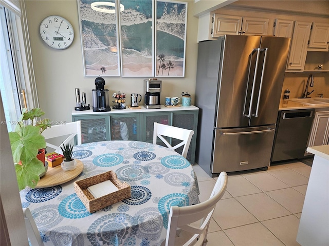 kitchen with dishwasher, light countertops, light tile patterned floors, high quality fridge, and a sink