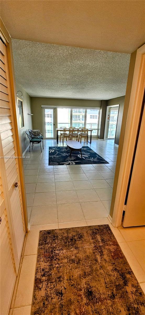 hall featuring tile patterned floors, plenty of natural light, and a textured ceiling