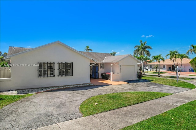 ranch-style home featuring aphalt driveway, an attached garage, and stucco siding