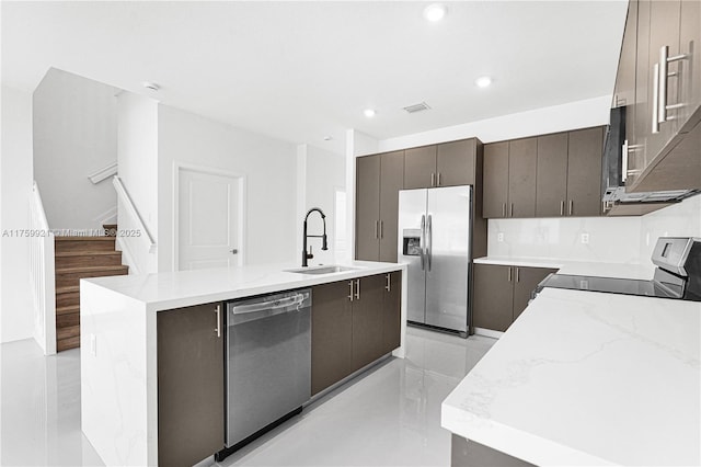 kitchen featuring visible vents, a kitchen island with sink, a sink, stainless steel appliances, and modern cabinets