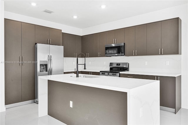 kitchen with visible vents, dark brown cabinets, light countertops, stainless steel appliances, and a sink