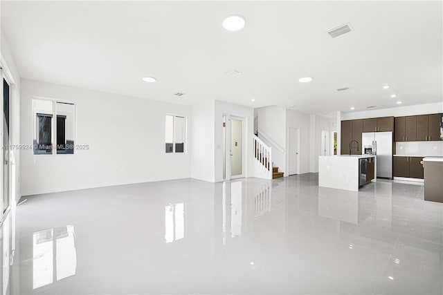 unfurnished living room featuring visible vents, recessed lighting, stairs, and a sink