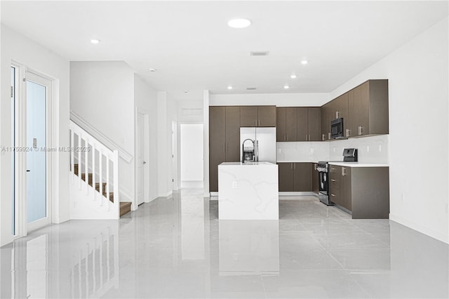 kitchen with dark brown cabinets, an island with sink, light countertops, appliances with stainless steel finishes, and modern cabinets