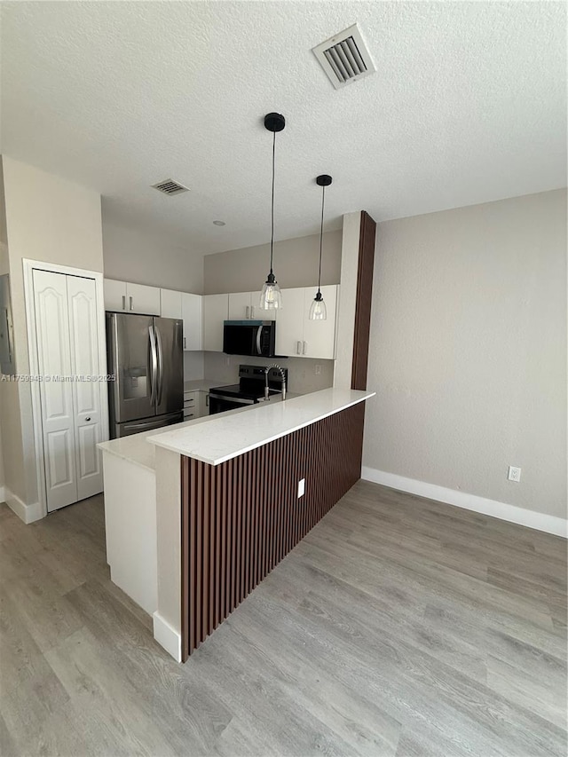 kitchen with visible vents, appliances with stainless steel finishes, a peninsula, and light countertops