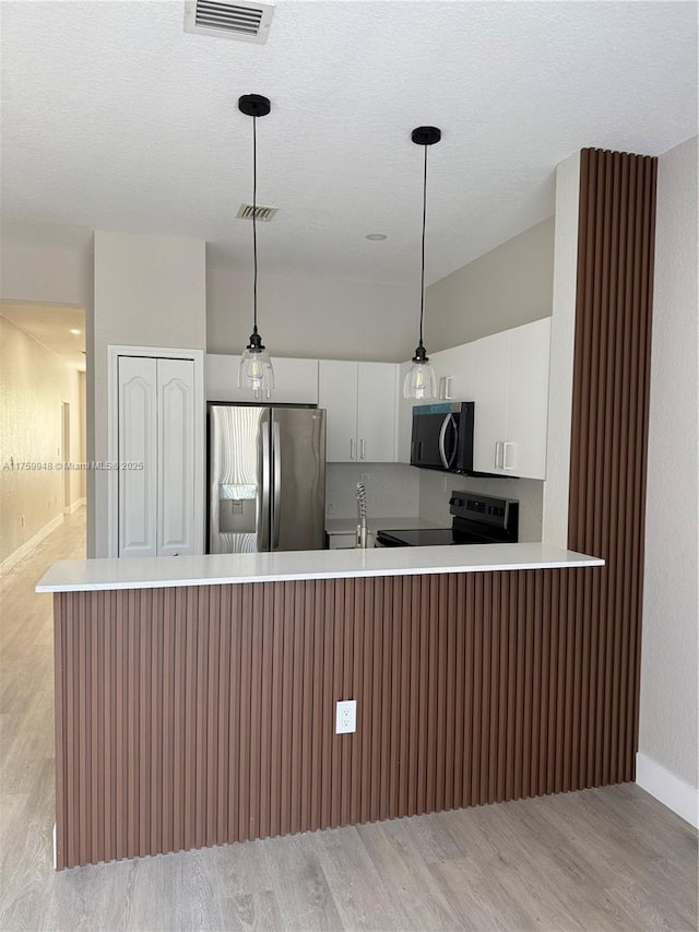 kitchen featuring light countertops, visible vents, stainless steel refrigerator with ice dispenser, and range with electric cooktop