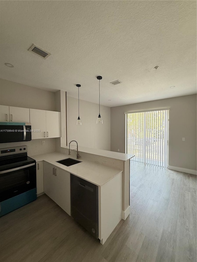 kitchen featuring visible vents, a sink, stainless steel appliances, a peninsula, and light countertops