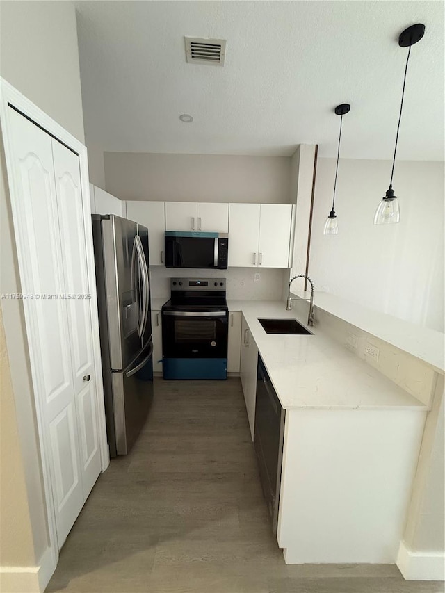 kitchen with visible vents, a sink, white cabinetry, stainless steel appliances, and light wood finished floors