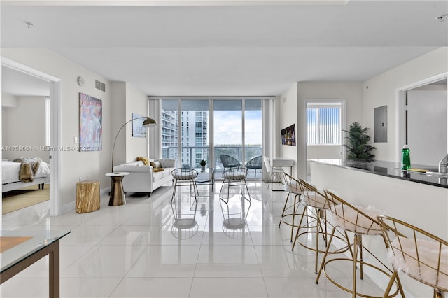 living area with tile patterned flooring, visible vents, floor to ceiling windows, and electric panel