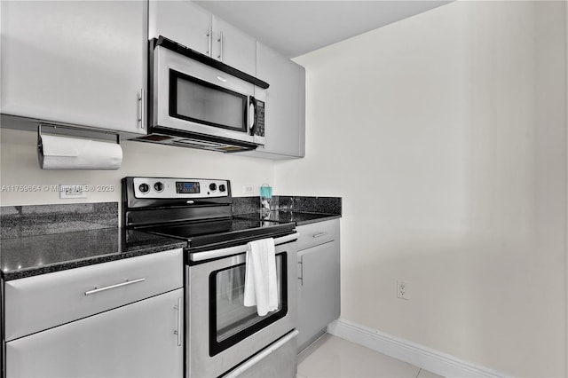 kitchen featuring stainless steel appliances, baseboards, white cabinetry, and dark stone counters