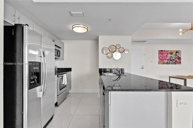 kitchen featuring light tile patterned floors, visible vents, a peninsula, a sink, and stainless steel appliances